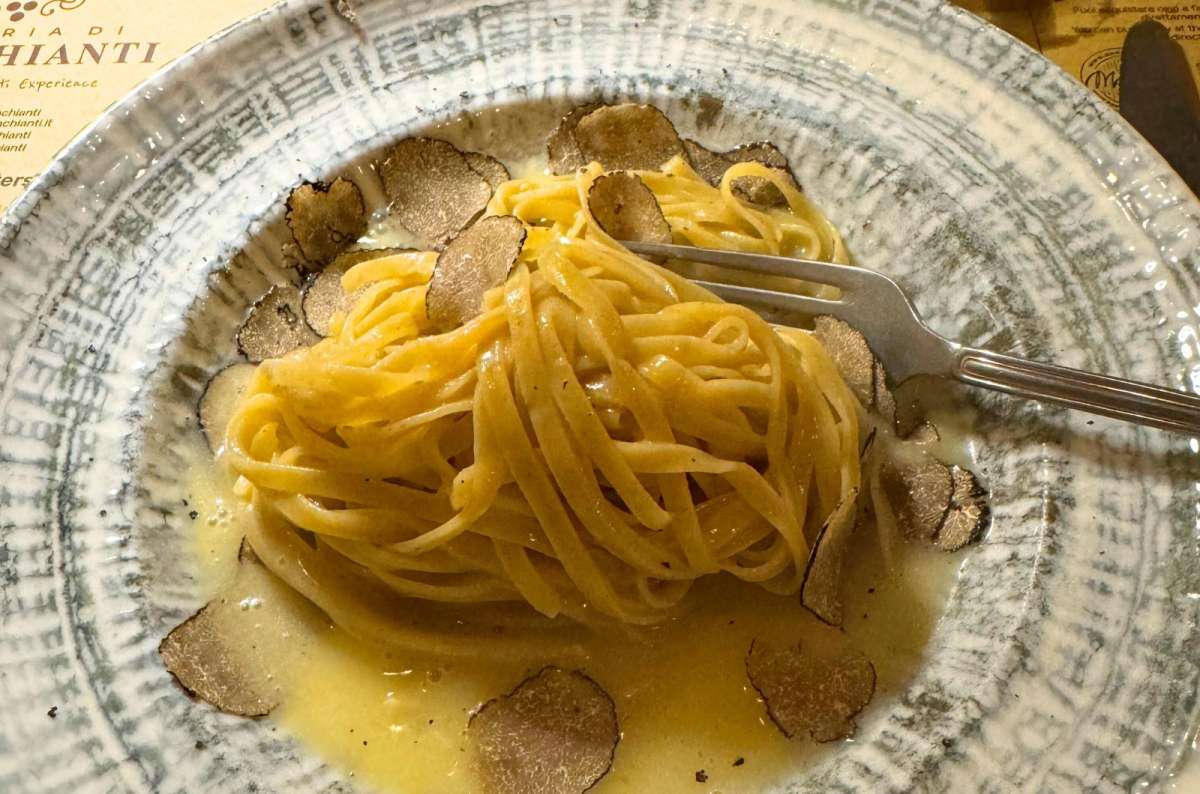Plate of tagliolini pasta served in a light butter sauce, topped with thinly sliced black truffles, Italy, photo by Next Level of Travel