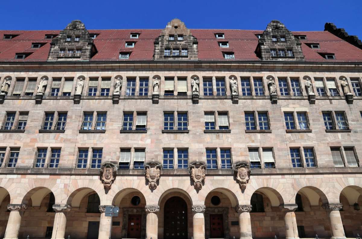 Front view of the Nuremberg Palace of Justice,  where the Nuremberg Trials were held after World War II, featuring arched entrances, multiple windows, and statues along the upper facade