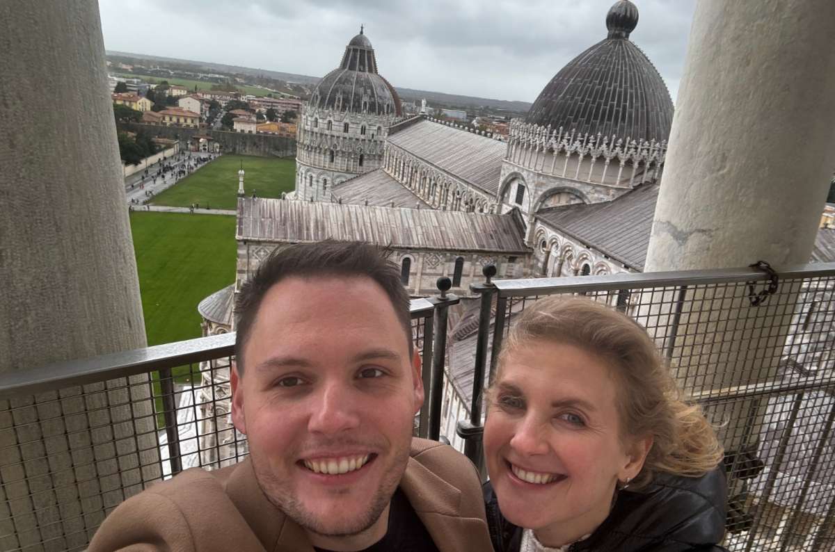 a tourist couple smiling on top of the leaning tower in Pisa, Italy, photo by Next Level of Travel