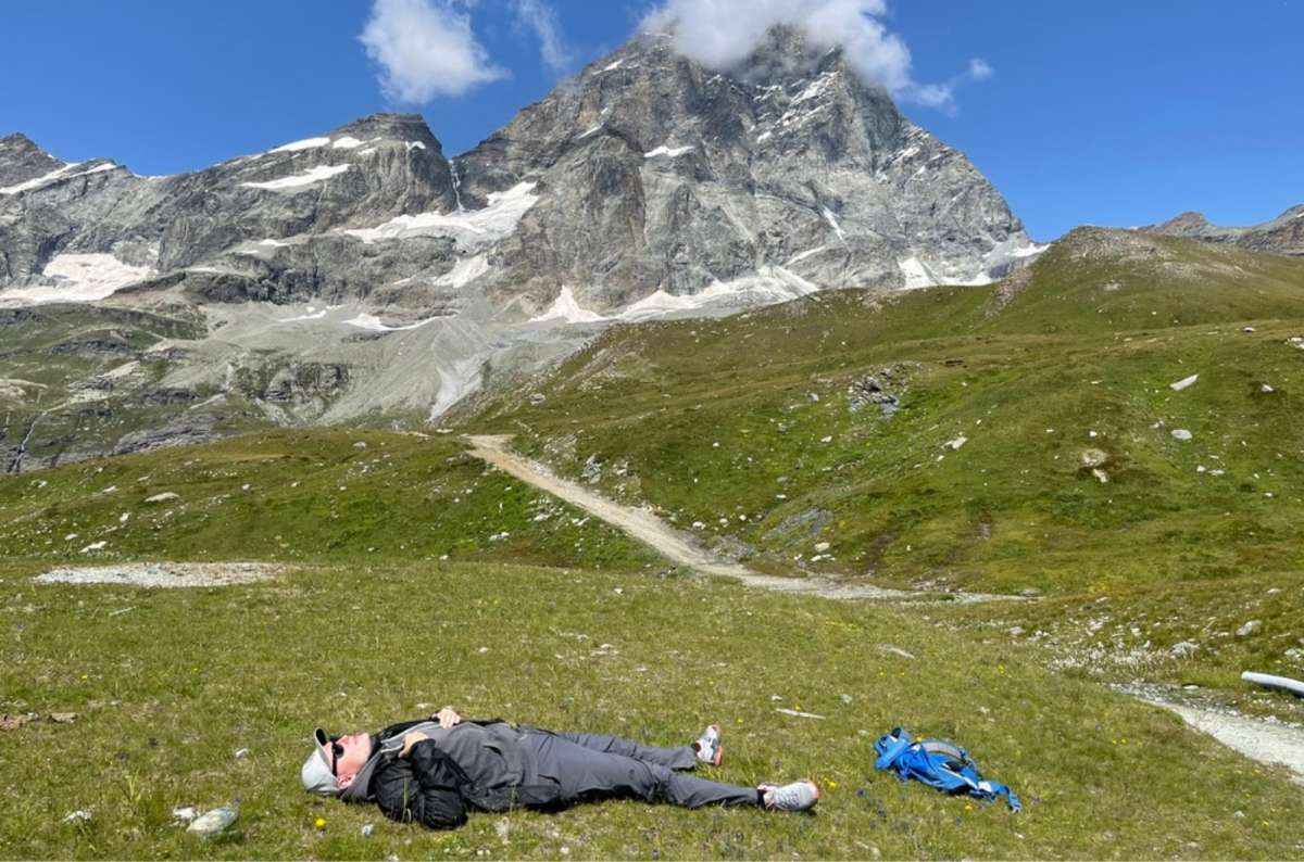 a tourist lying down in a meadow resting after hiking up the Matterhorn, Italy, photo by Next Level of Travel