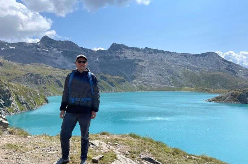 A tourist in front of Lago Blu with mountain visible in the background, photo by Next Level of Travel