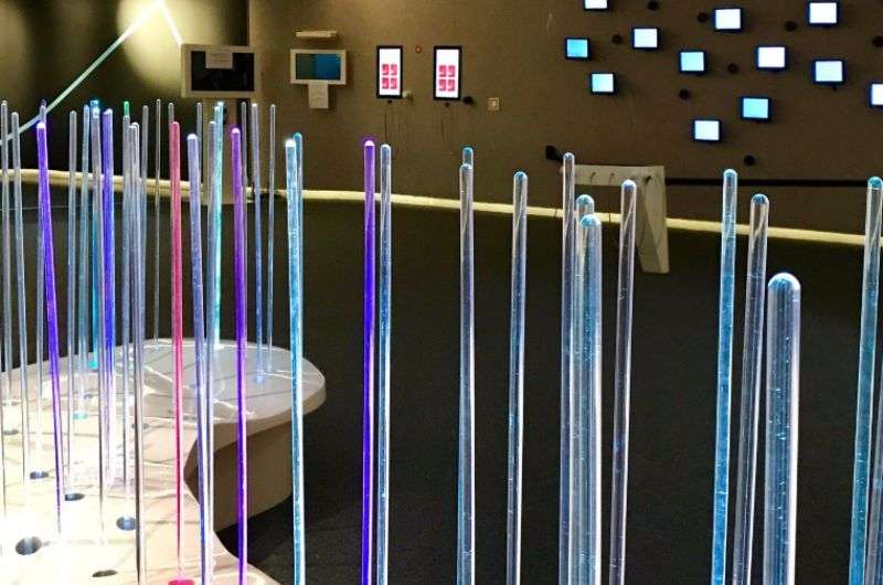 A futuristic exhibit at the Audioversum Science Center, featuring illuminated glass rods and interactive sound displays, Austria
