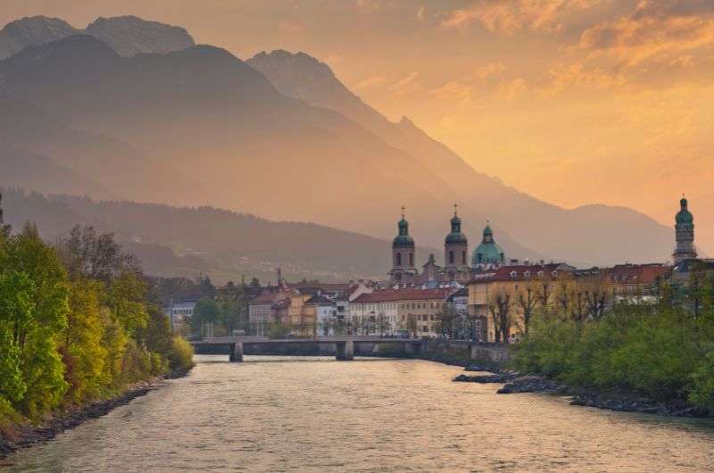 A row of colorful houses along the river in Innsbruck, with snow-covered mountains, Autria