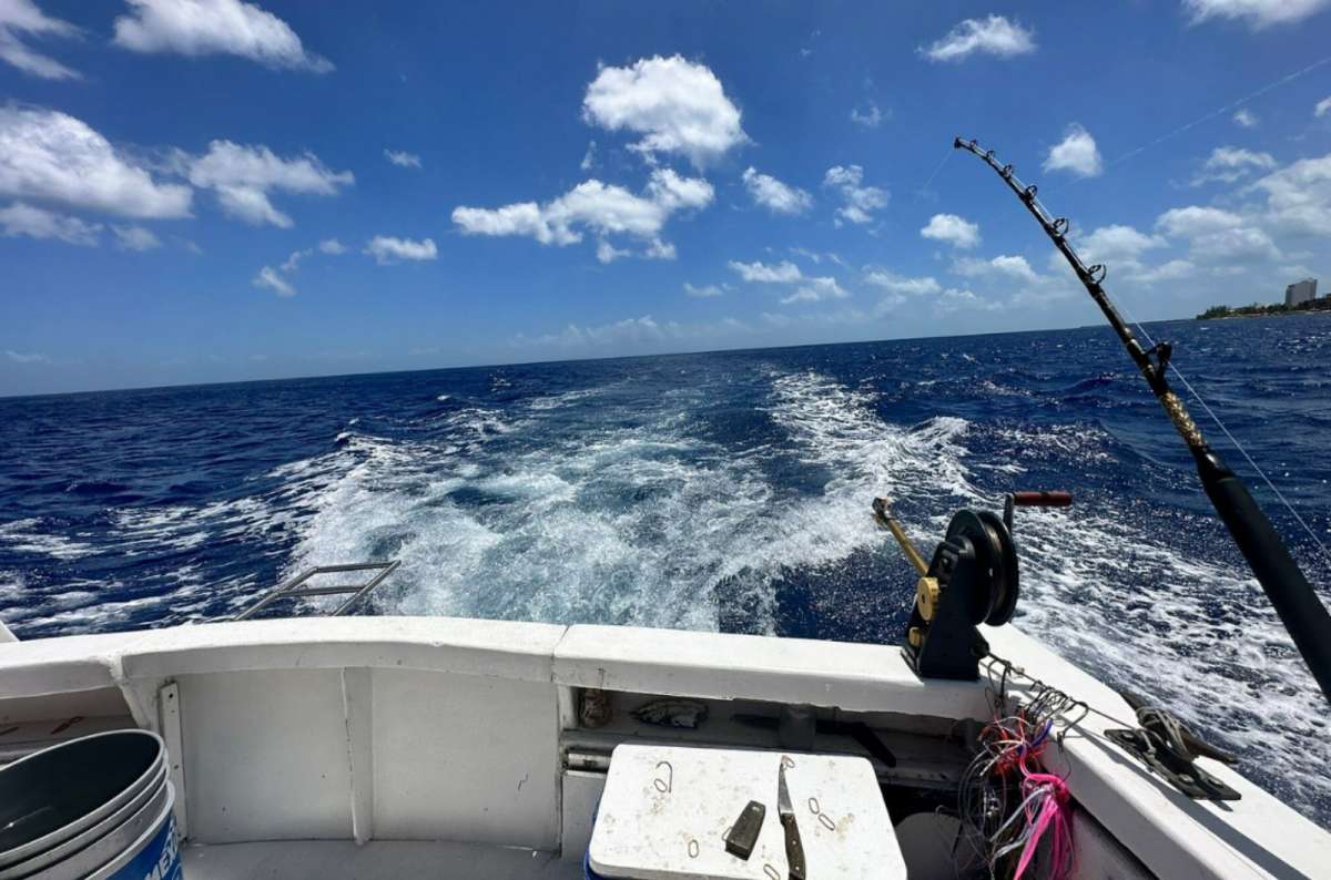 The back of a deep sea fishing boat cruising off the coast of Cozumel Island, Mexico, with fishing rods and open Caribbean Sea 