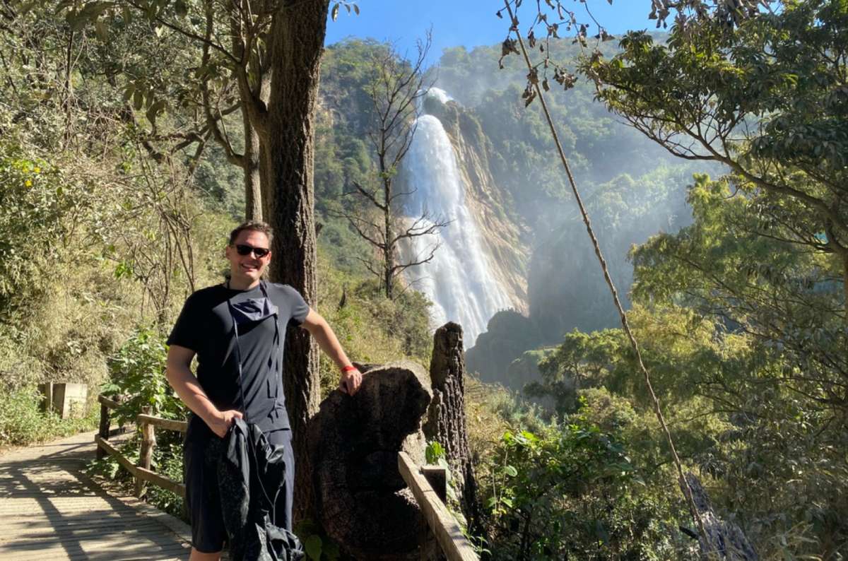 a photo of a tourist standing beside a turquoise pool lined with cypress trees at one of El Chiflón's waterfalls, Mexico, photo by Next Level of Travel