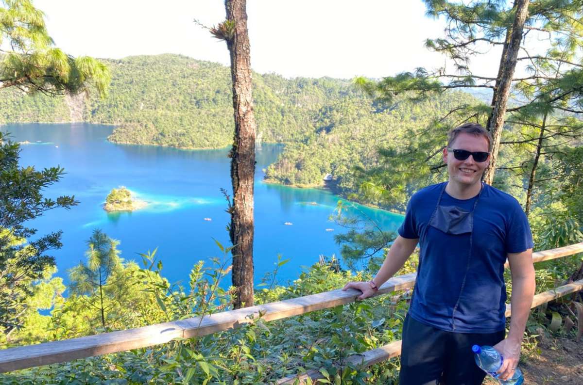a tourist posing at a viewpoint in front of a lake at Chiapas, with forests visible in the background, Mexico, photo by Next Level of Travel