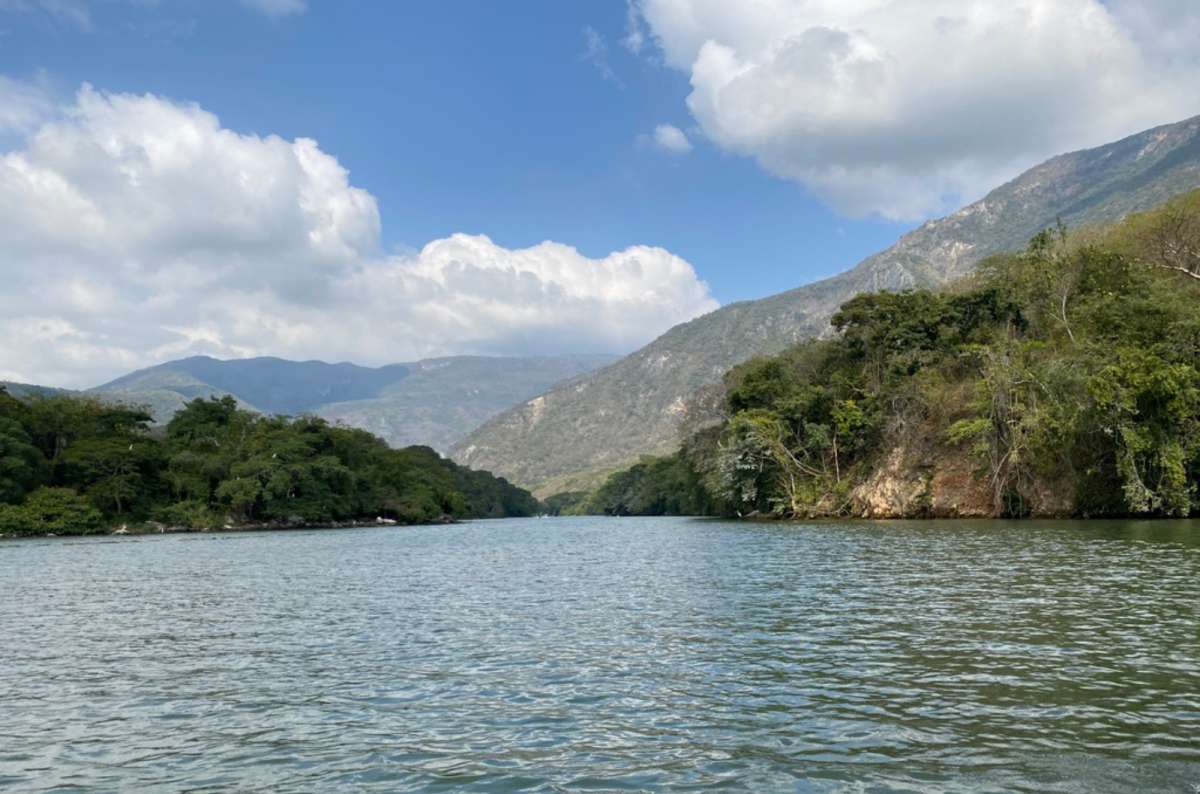 a photo from the Sumidero Canyon showing the surrounding rock fromations covered in greenery under the blue sky, Mexico, photo by Next Level of Travel