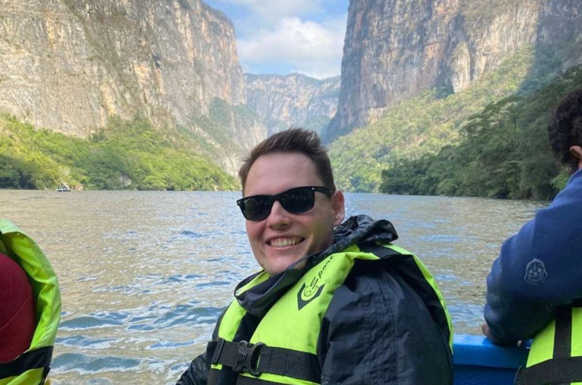 a photo of a tourist posing on a raft in a yellow life jacket, during a cruise in the Sumidero Canyon, with the cliffs and the water visible in the background, Mexico, photo by Next Level of Travel