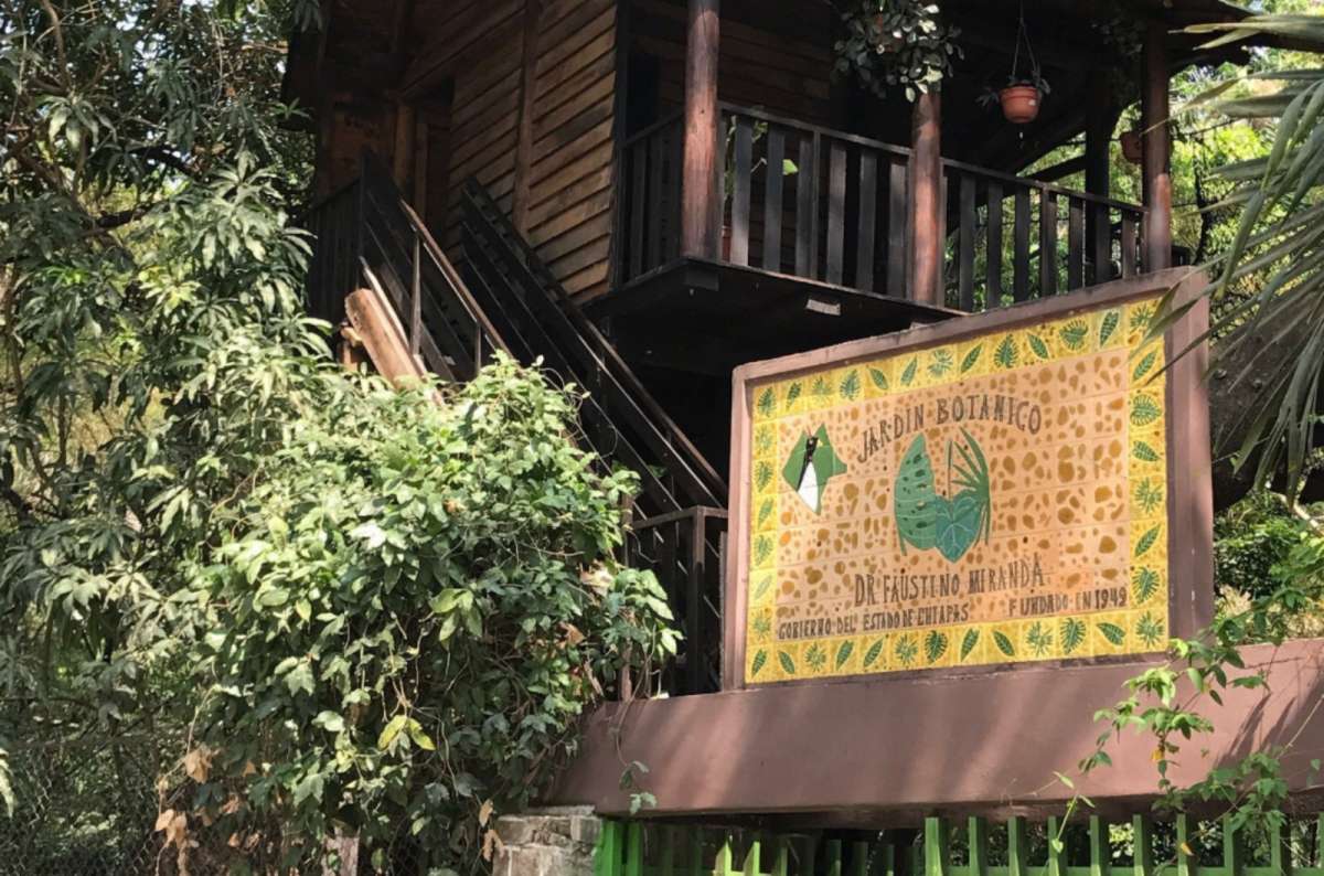 a photo of the entry sign to the Faustino Miranda Botanical Garden surrounded by beautiful green trees, Mexico