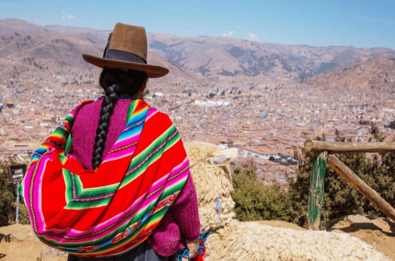 Peruvian woman in traditional clothing looking out at a view in Peru 