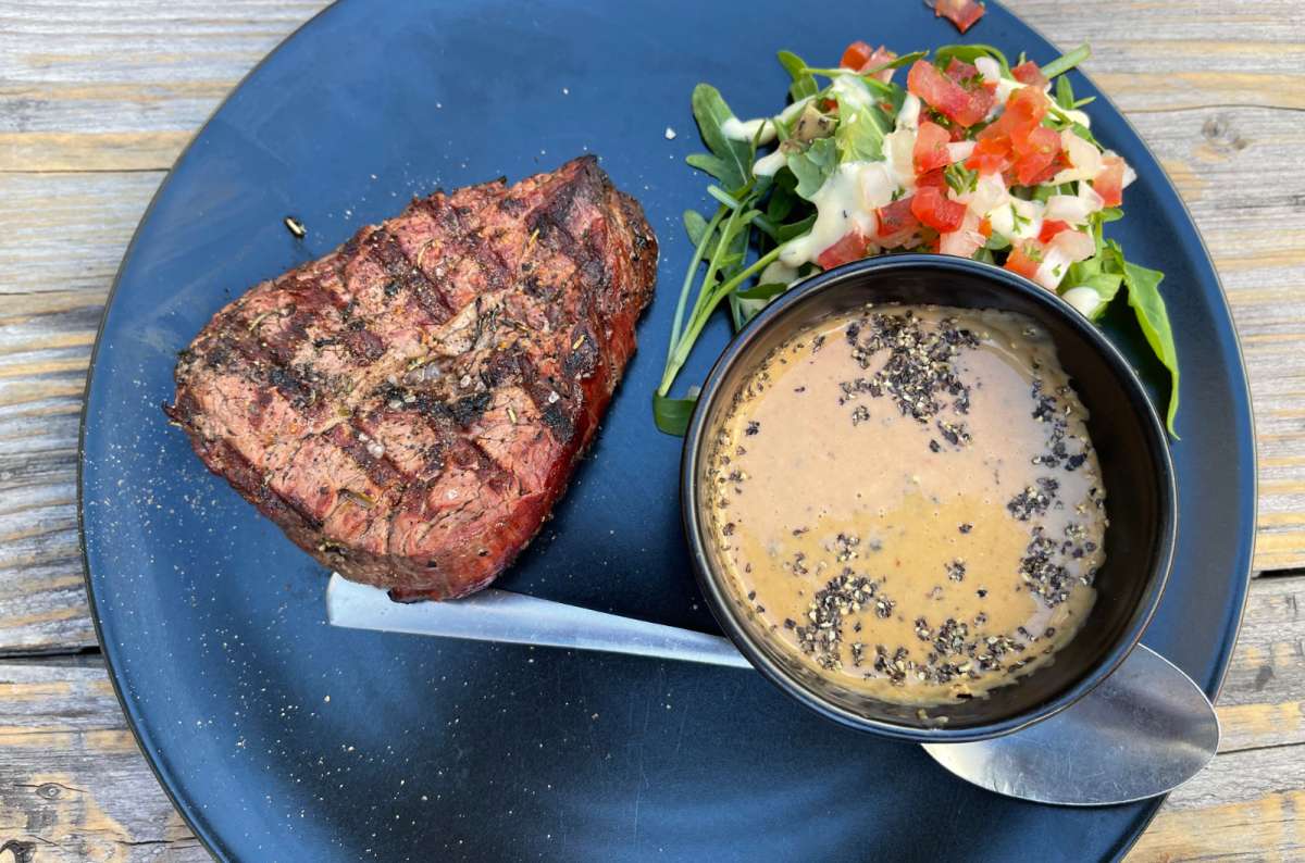 Grilled steak with creamy pepper sauce and side salad served on a black plate at a Belgian restaurant, photo by Next Level of Travel