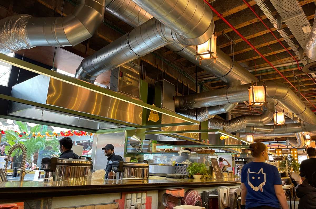 Open kitchen view at Wolf Food Market in Brussels, with industrial-style ventilation, staff at work, photo by Next Level of Travel