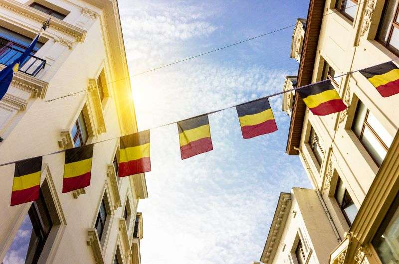A line of Belgian flags between two historical buildings in Belgium