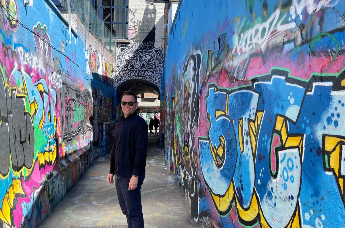Colorful graffiti alley in Werregarenstraat, Ghent, Belgium, with a smiling tourist,  photo by Next Level of Travel