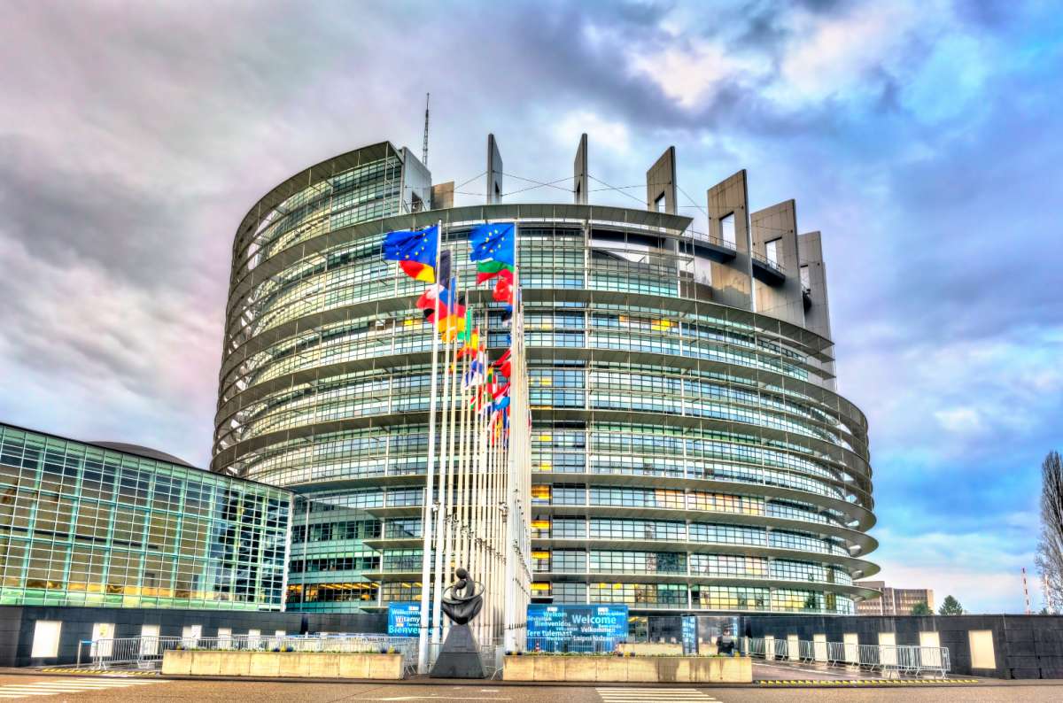 a photo of the European Parliament building, showing off its modern architecture and a variety of flag of the EU member countries, Brussels, Belgium