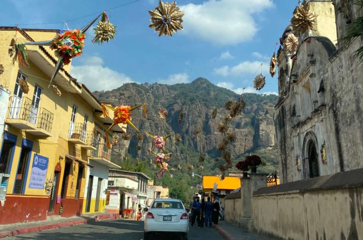 a photo of a colorful street in Puebla decorated with piñatas in a colonial Mexican town with dramatic rocky cliffs in the background, Mexico, photo by Next Level of Travel