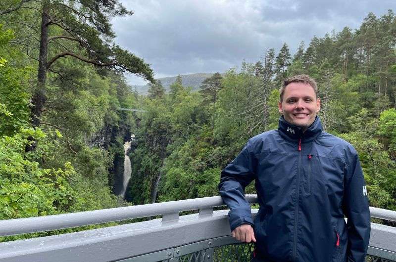 A tourist in front of the Measach Falls, Scotland