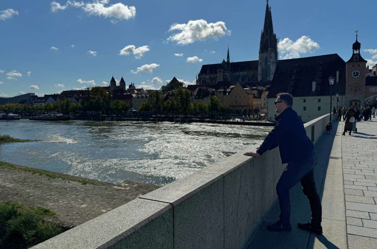 A tourist looking into the distance at the Regensburg Roman Stone Bridge, Bavaria travel itinerary, photo by Next Level of Travel