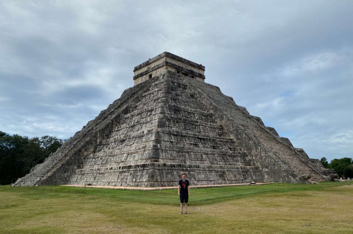 a photo of a tourist standing in front of the El Castillo pyramid at Chichén Itzá, Mexico, photo by Next Level of Travel