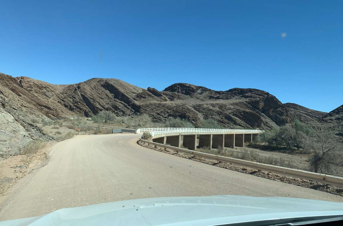 a photo of a gravel road winding through a rocky canyon landscape in Namibia, taken from inside a 4x4, photo by Next Level of Travel