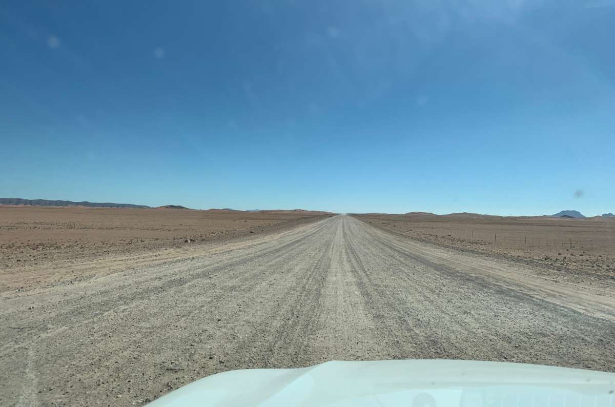 a photo of an endless gravel road stretching through the barren Namibian desert, taken from inside a 4x4, Namibia, photo by Next Level of Travel