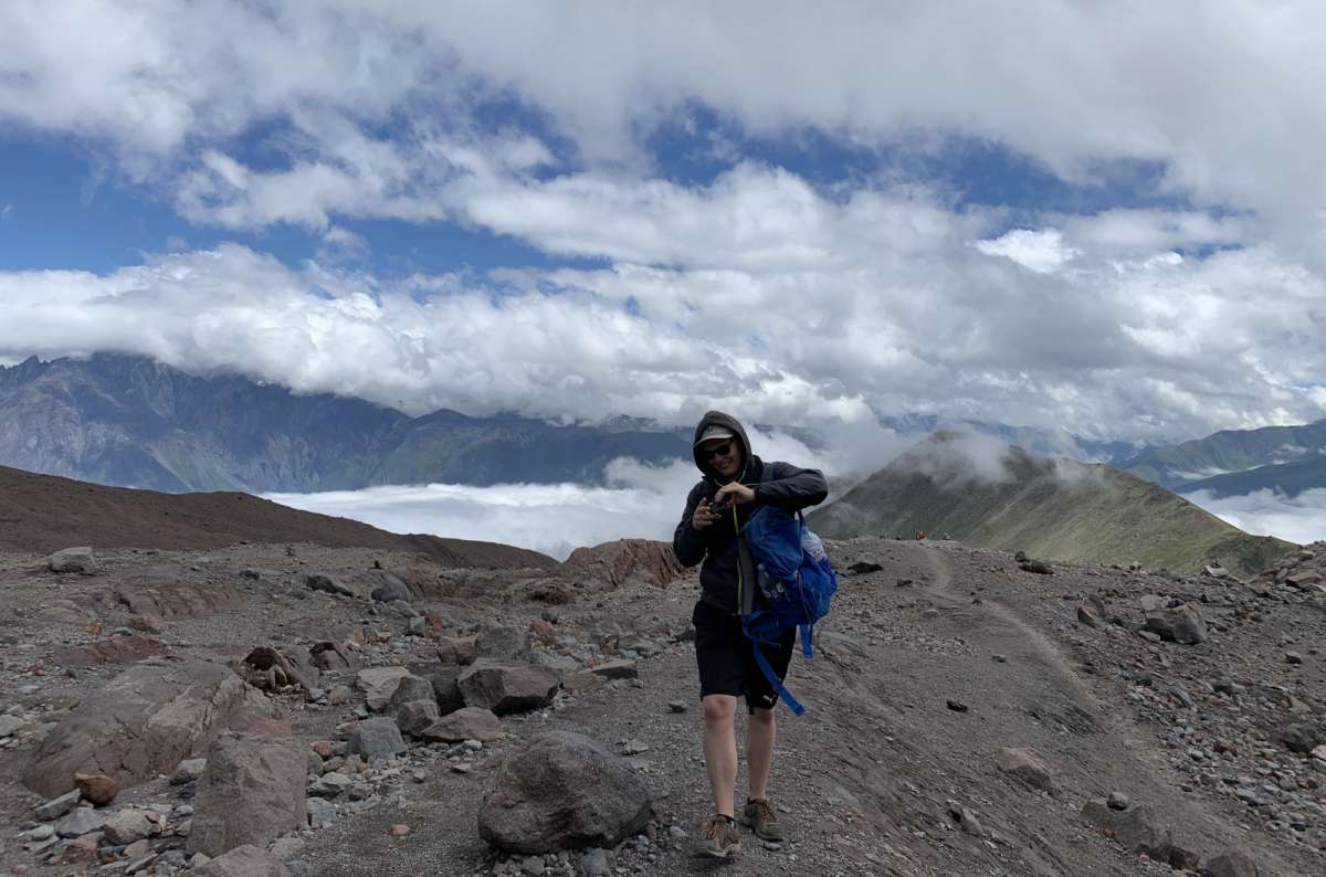 a photo of a tourist in the middle of the Georgian Kazbeg mountains, photo by Next Level of Travel