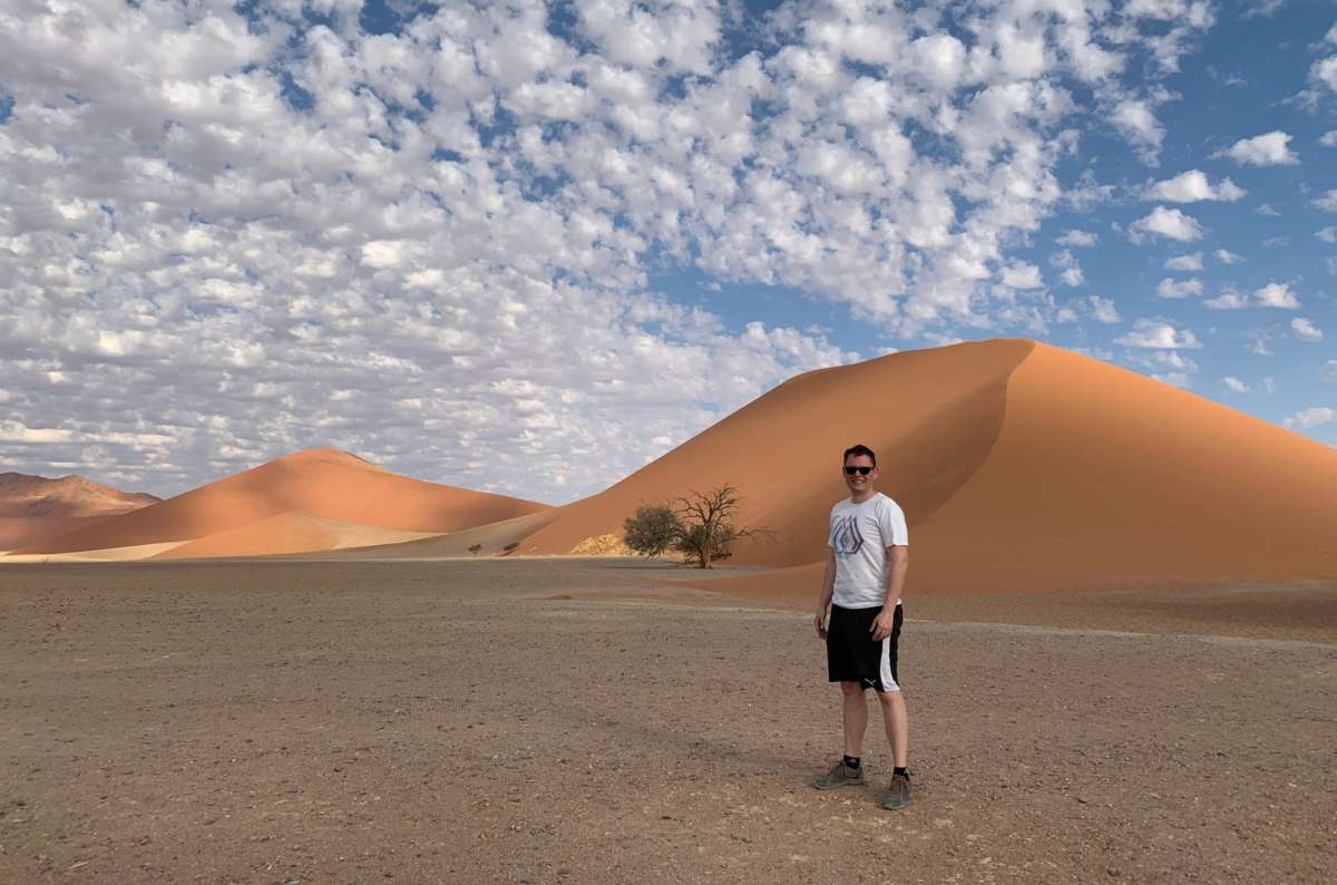 Tourist standing by sand dunes in Sossusvlei, Namib Desert, Namibia, photo by Next Level of Travel