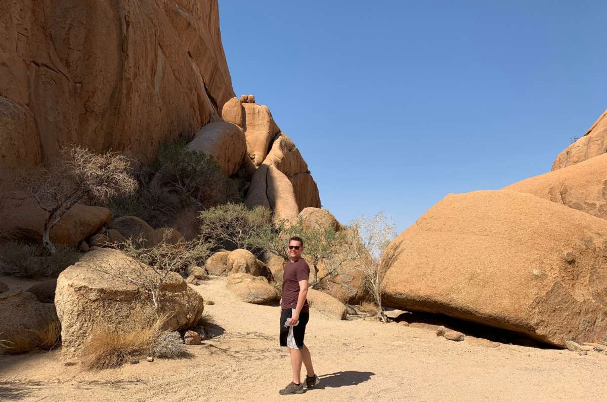 a photo of a tourist exploring the dramatic granite rock formations at Spitzkoppe in Namibia, photo by Next Level of Travel