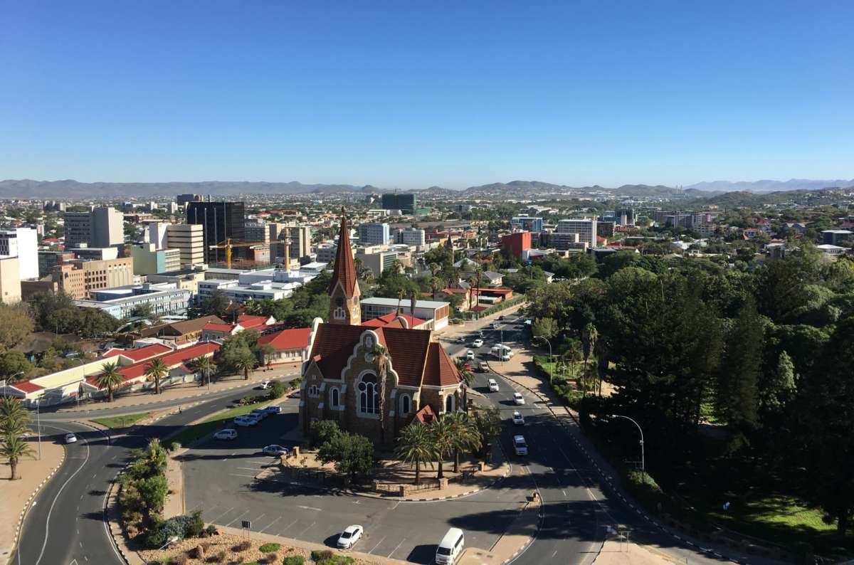 a photo of the Windhoek city skyline with the iconic Christuskirche church in the foreground and the Namibian mountains visible in the background, photo by Next Level of Travel
