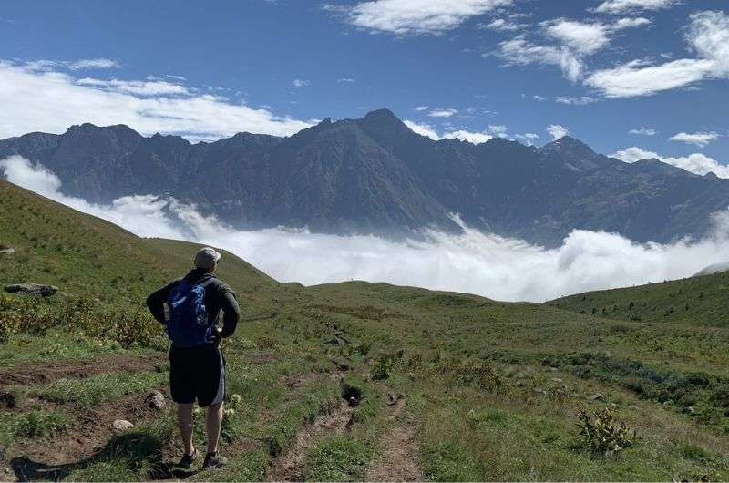 Tourist staring at Kazbeg Mountains above the clouds, Georgia best hikes