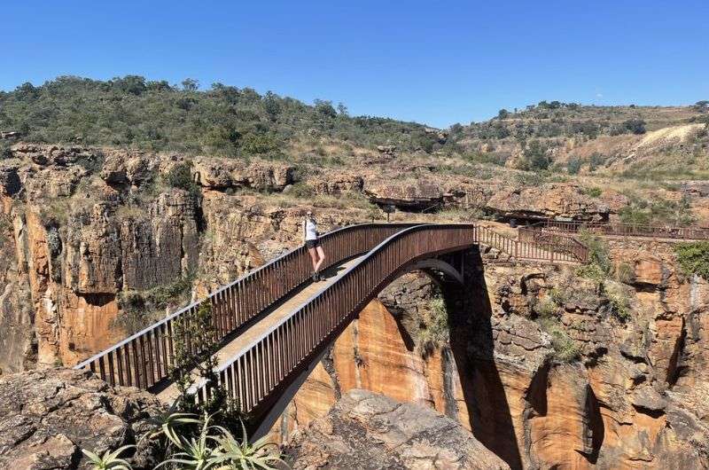 Woman standing on a bridge on Panorama ROute, where travel is safe for females in South Africa