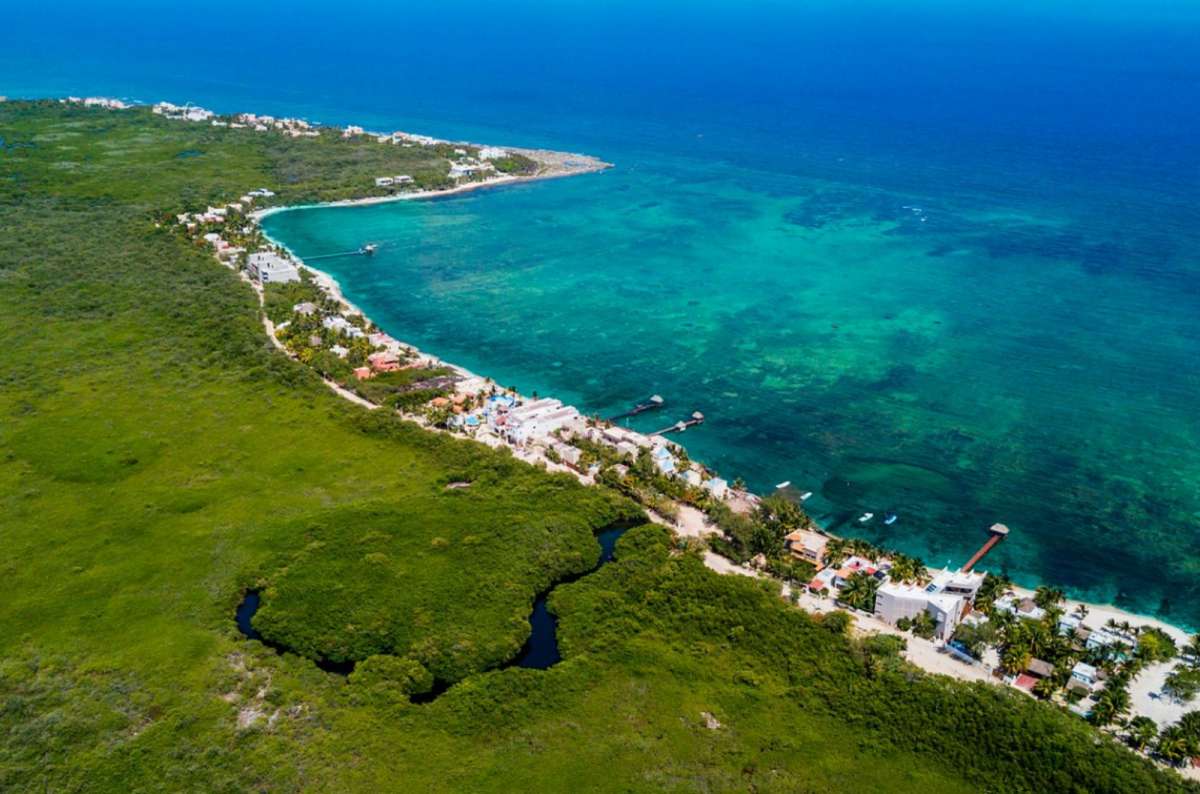 Aerial view of the coastline near Tulum, Mexico, showing turquoise Caribbean waters, mangroves, and low-rise beachfront accommodation along the Yucatán Peninsula