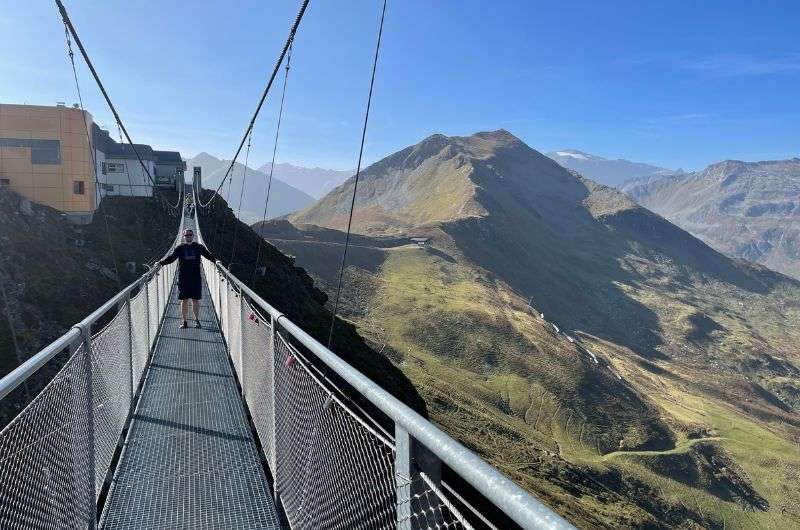 Hiker standing on a suspension bridge with stunning alpine views in Austria, a highlight of hiking in Bad Gastein and one of the best hikes in Austria, photo by Next level of travel