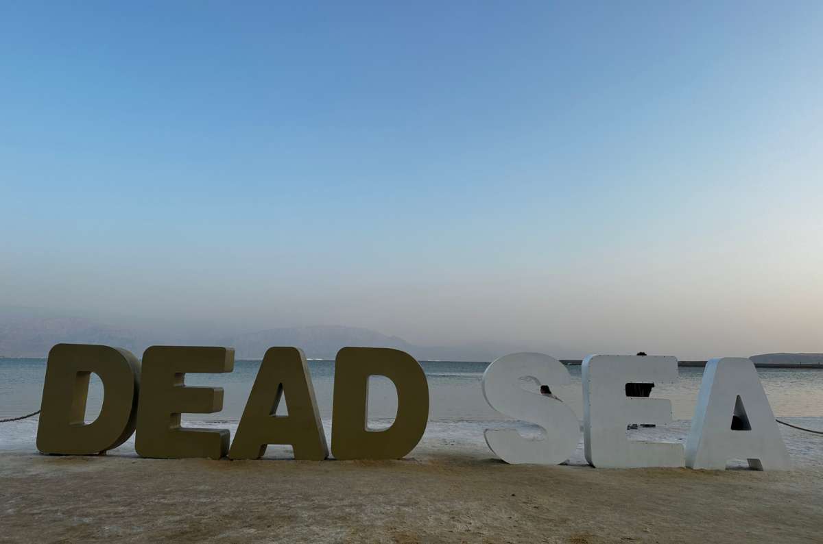 Large “Dead Sea” sign on the sandy shore of the Dead Sea in Israel, photo by Next Level of Travel