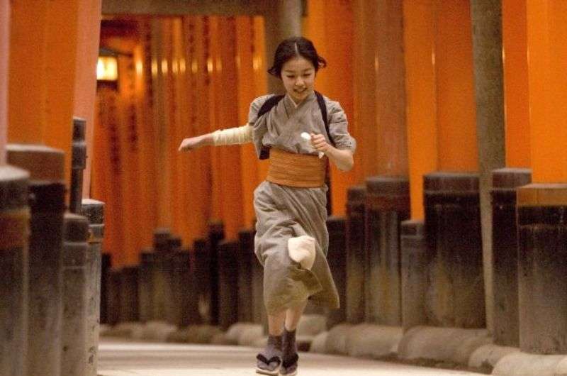 Geisha running through the Torii gates in Fushimi Inari Taisha Shrine in Kyoto, Japan