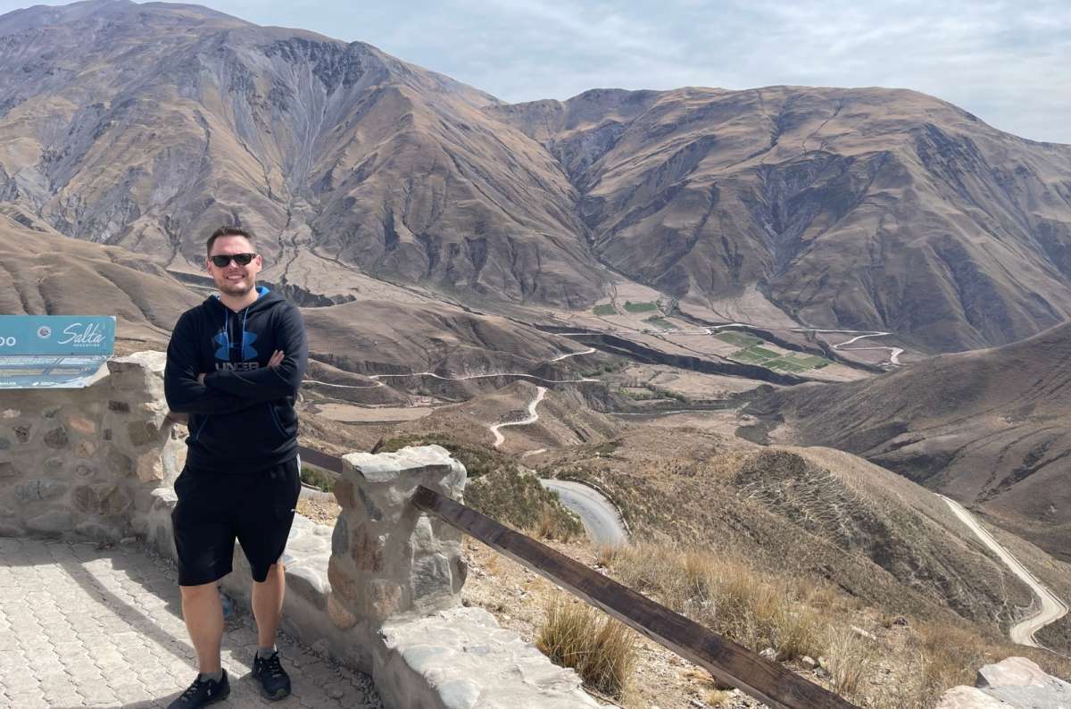 : A tourist standing at Salta Cuesta del Obispo, Argentina, hills and valleys visible in the background, photo by Next Level of Travel