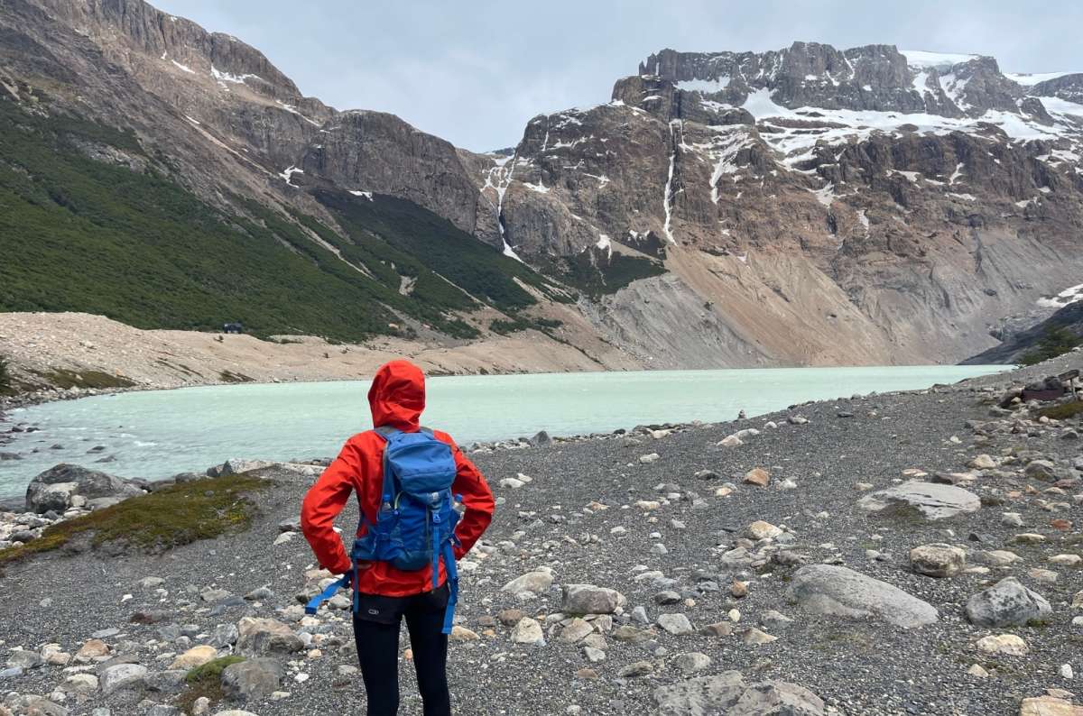 Hiker standing by a glacial lake surrounded by mountains, Laguna El Diablo, Argentina, photo by Next Level Travel