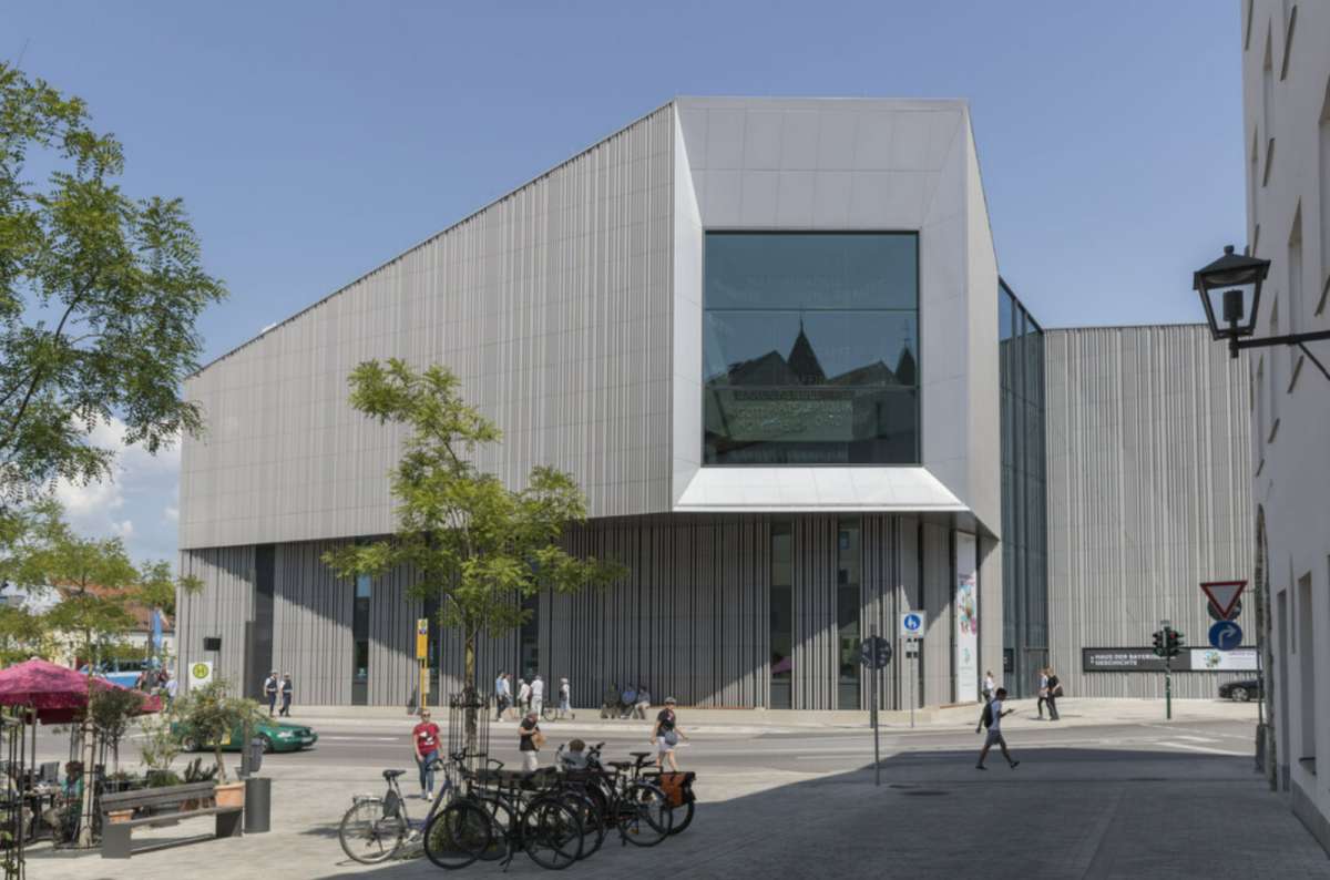 Modern angular building of the House of Bavarian History in Regensburg, Germany with a large glass window and people walking and cycling in front