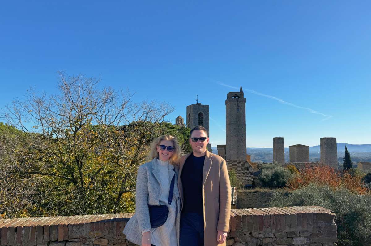 a photo of a couple posing in front of the view from one of the San Gimignano towers, Italy, photo by Next Level of Travel