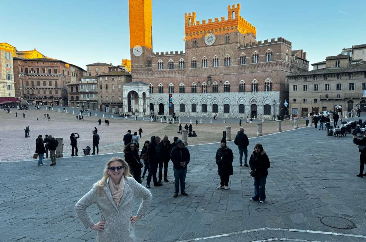 a woman posing at Piazza dei Campo with lots of other tourists in the background during one day in Siena, photo by Next Level of Travel