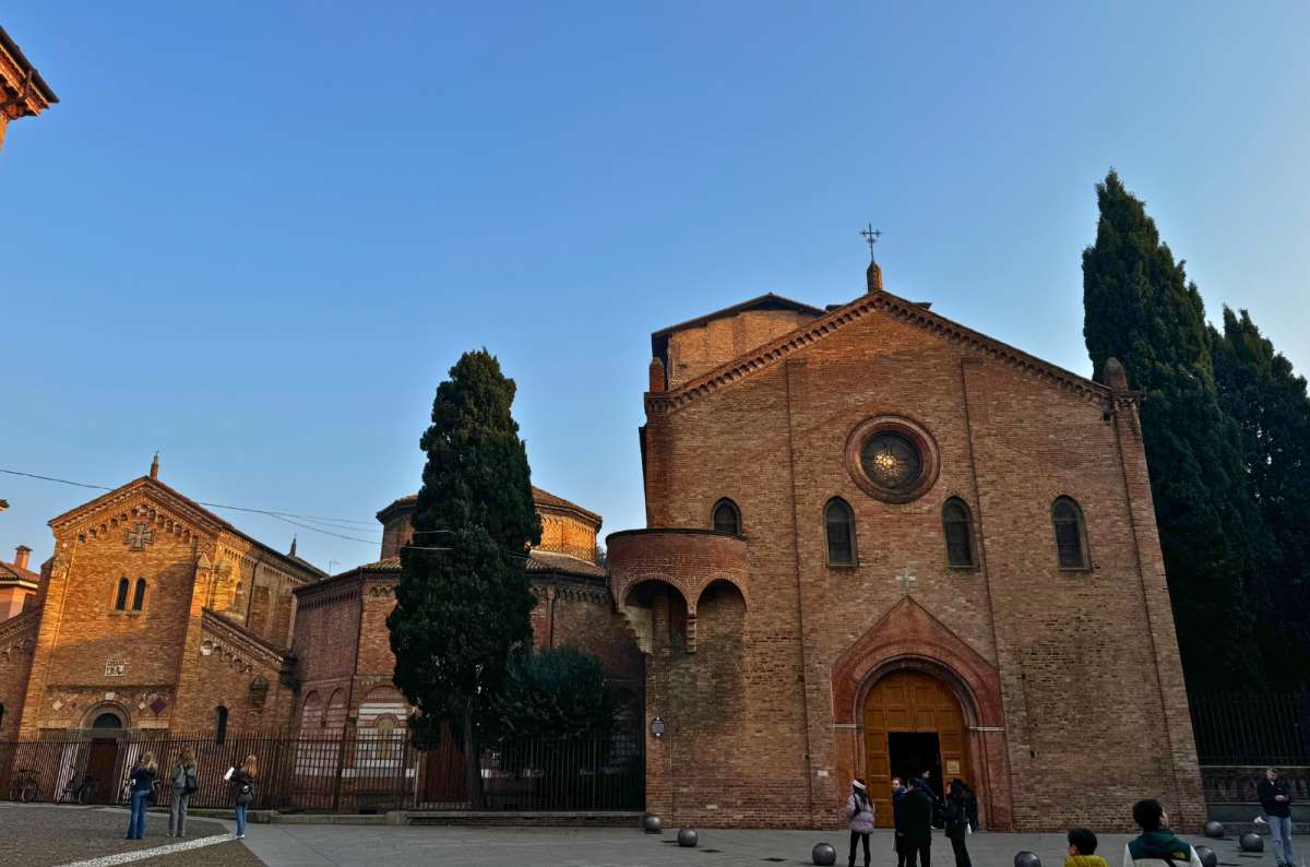 Exterior of the Basilica of Santo Stefano in Bologna, Italy, with its red brick façade and round stained glass window, photo by Next Level of Travel