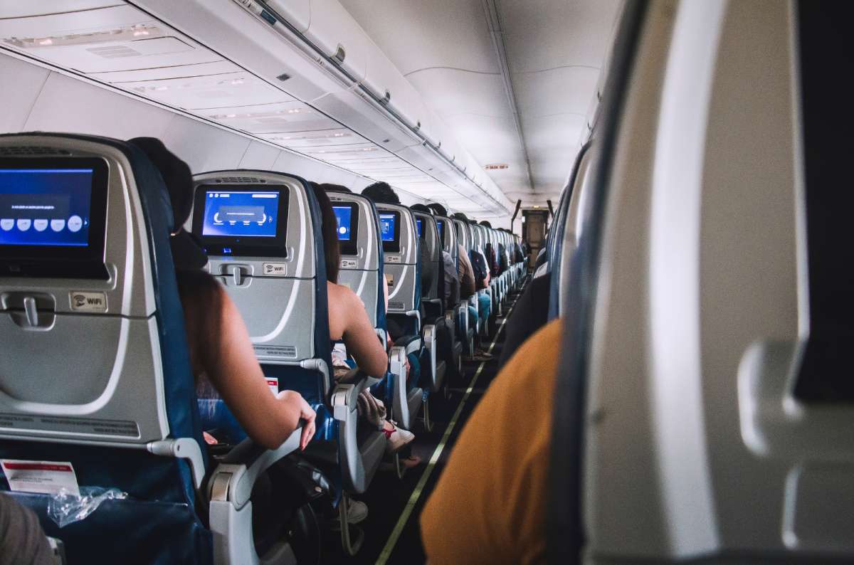 Airplane interior showing standard Economy Class seating with individual entertainment screens