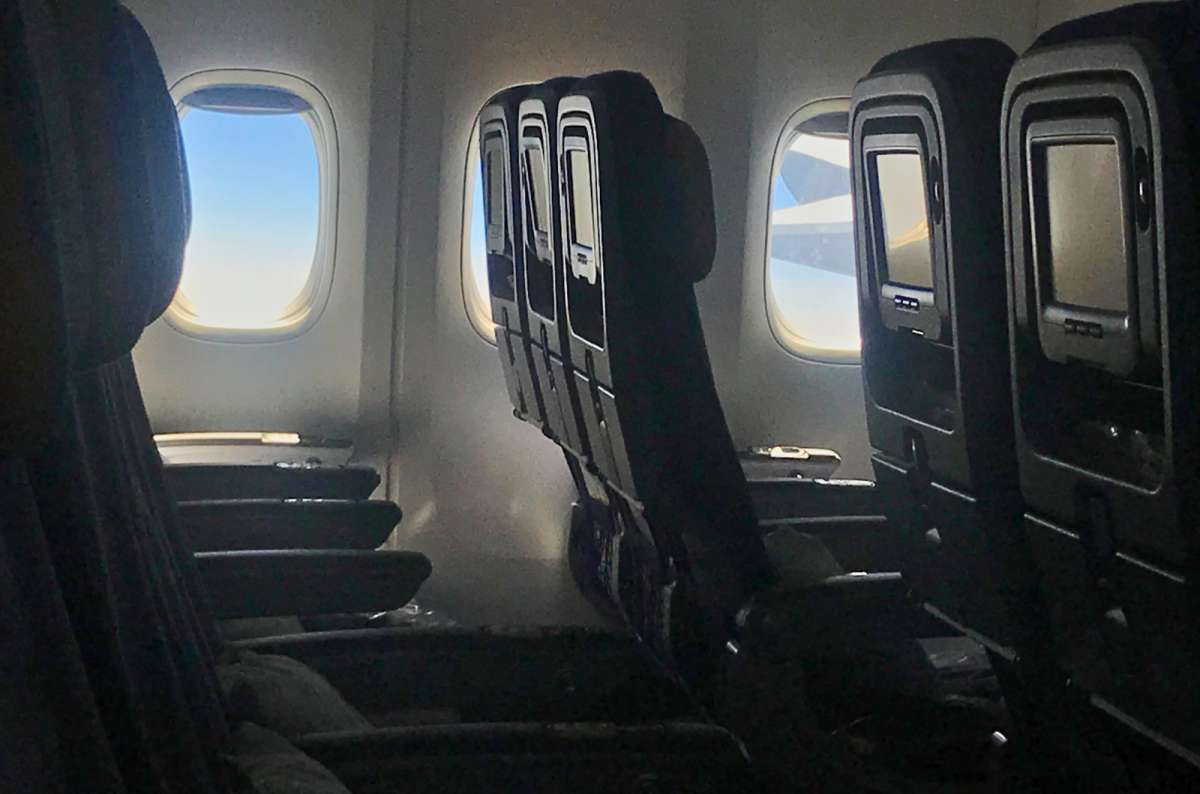 Standard Economy Class airplane seats with seatback screens and limited legroom, view from inside the cabin, photo by Next Level of Travel