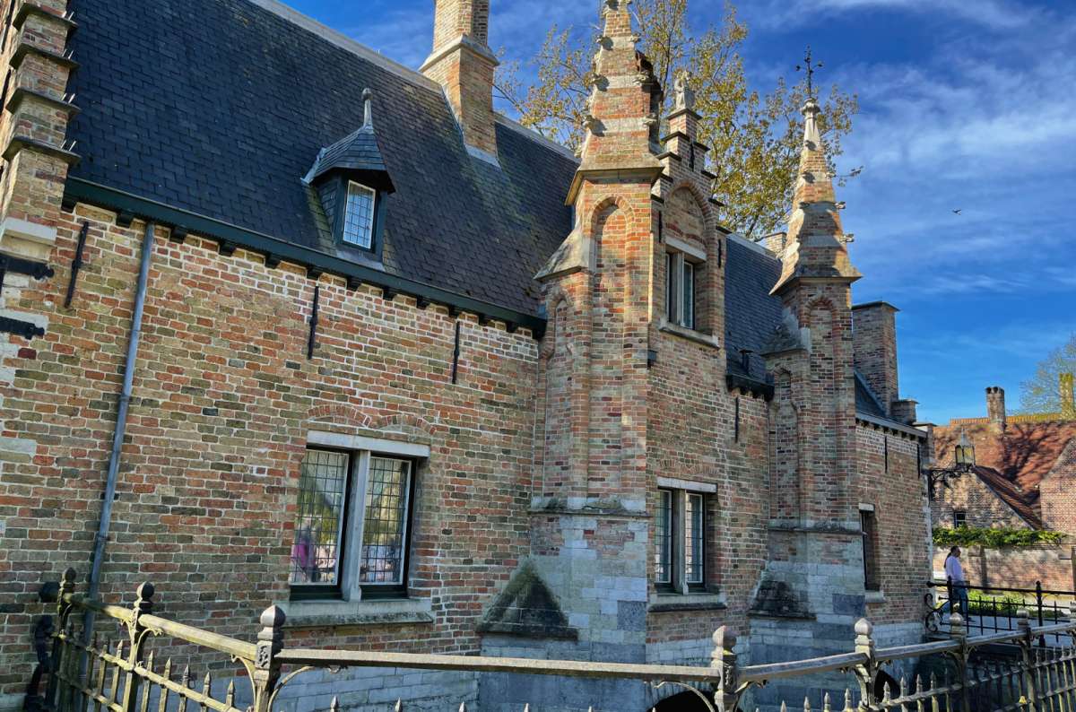 Historic brick building at the Beguinage in Bruges, Belgium, with gothic architectural elements and arched windows, photo by Next Level of Travel