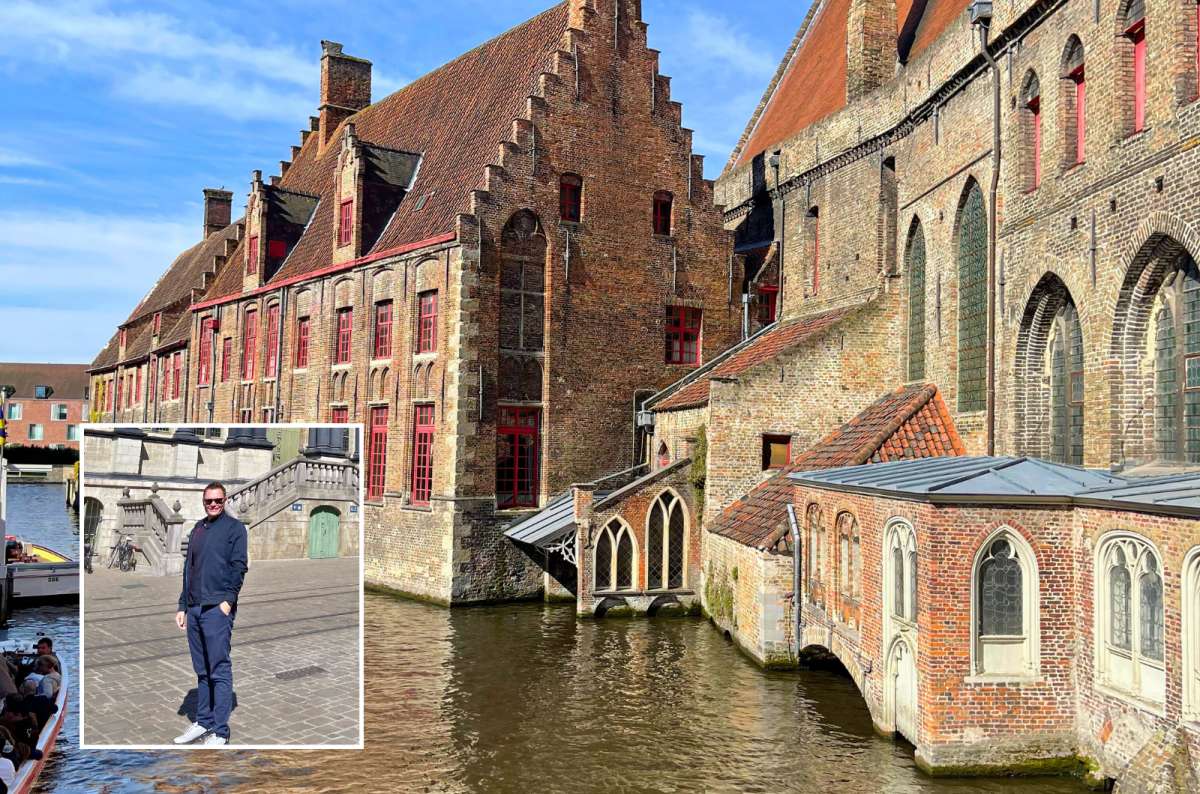 Historic brick buildings along the canal in Bruges, Belgium, with red-framed windows and a man posing in the inset photo, photo by Next Level of Travel