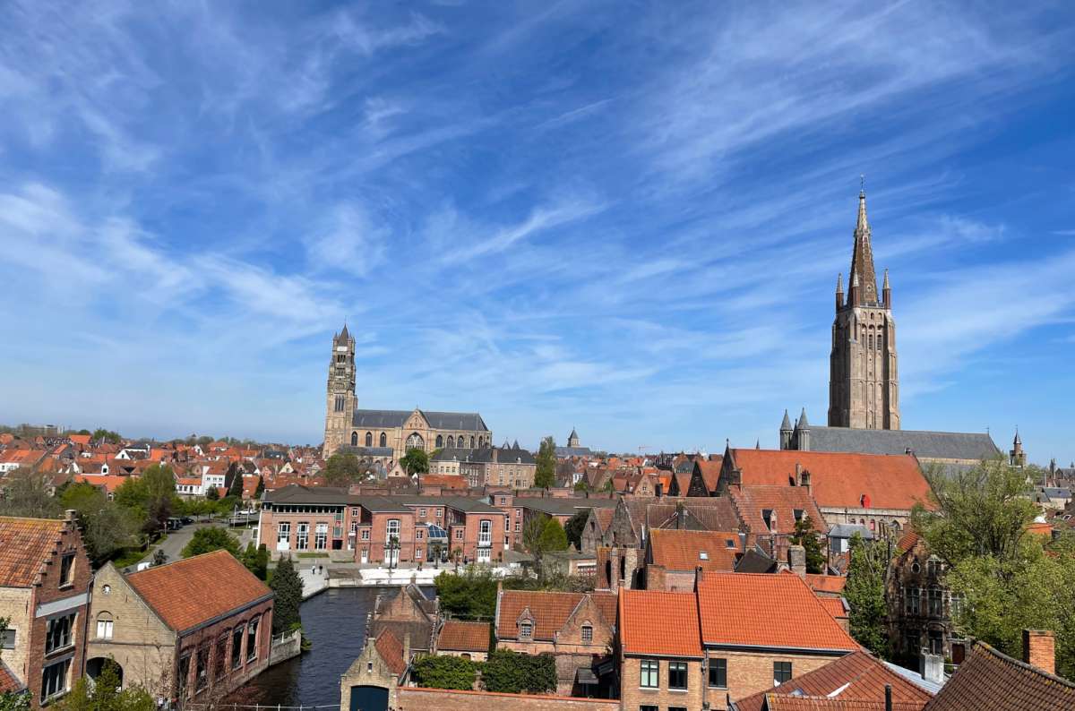 Scenic aerial view of Bruges’ car-free historic center with towers and red rooftops, photo by Next Level of Travel
