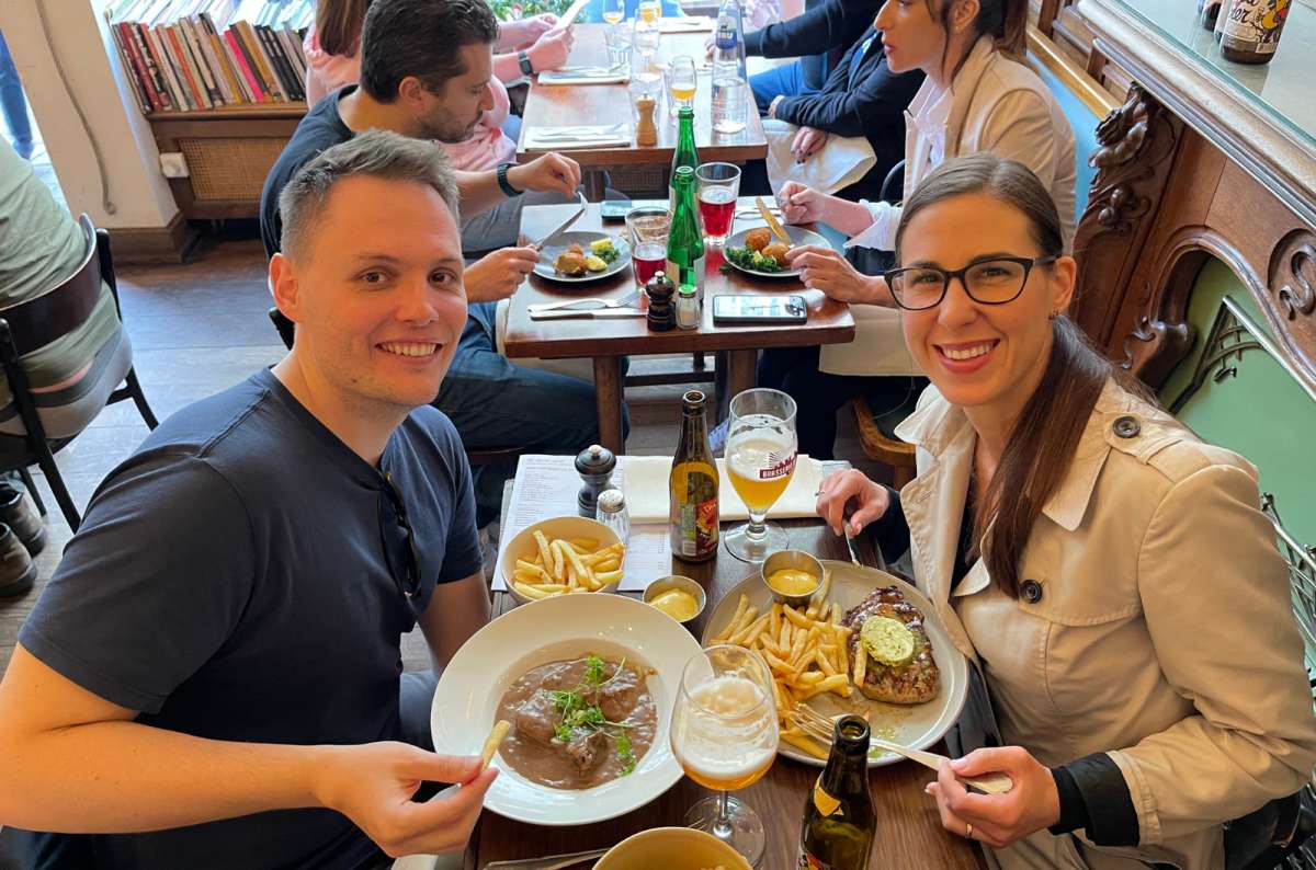 Tourists enjoying traditional Belgian food with beer, steak, fries, and stoofvlees stew in Brussels, Belgium, photo by Next Level of Travel