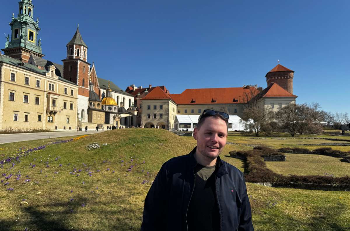 a photo of a tourist posing in front of the Wawel Castle, Krakow, Poland, photo by Next Level of Travel