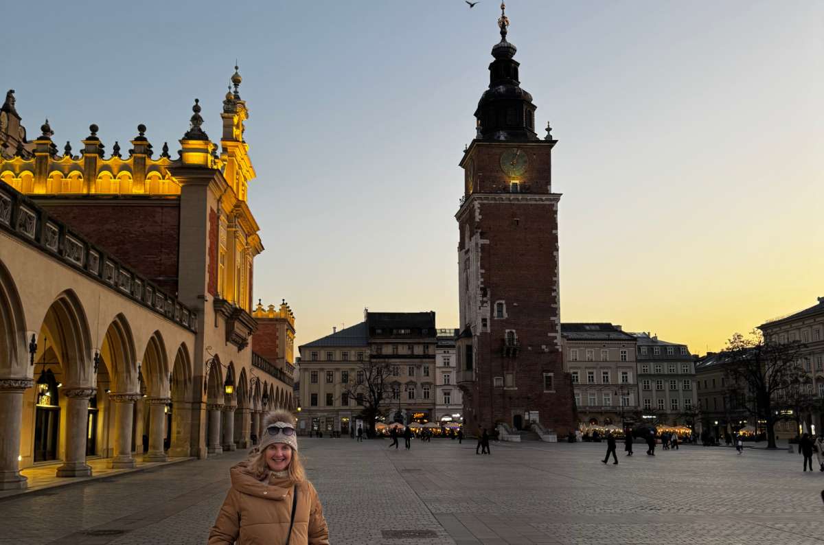 a photo of the Main Square with a tourist posing in front of the Town Hall, Krakow, Poland, photo by Next Level of Travel