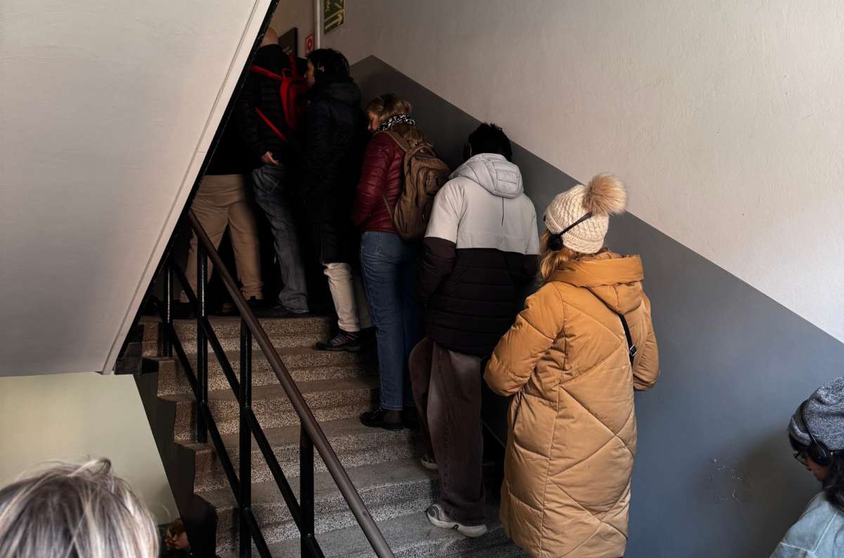 a photo of a crowd standing on a flight of stairs, patiently waiting in a line, Oświęcim, Poland, photo by Next Level of Travel